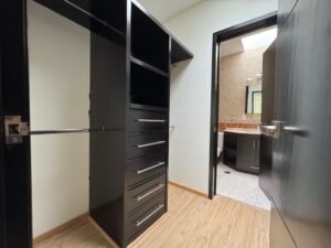 Vestidor de la recámara principal con acabados en madera oscura en casa en condominio horizontal en venta cerca del Club de Golf